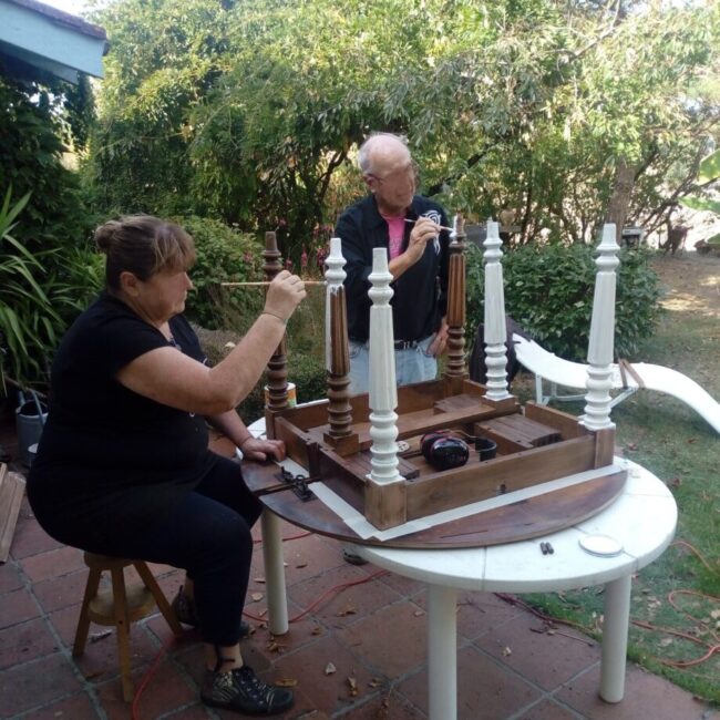 Cette image représente des clients en train de peindre leur table au cours d'un atelier à domicile avec Laurence Boglio